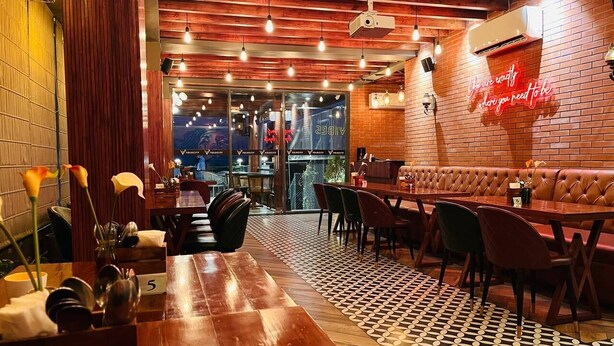A restaurant interior with wooden tables, leather booths, and a patterned floor. - Hotel Palampur Life (Palampur)