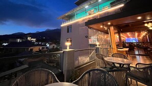 A rooftop terrace with outdoor seating and a view of the mountains. - Hotel Palampur Life (Palampur)