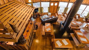 A wooden interior with benches and tables, a sofa, and a fireplace. - Neltume Lodge (Panguipulli)