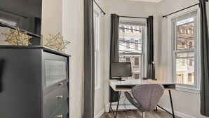Une chambre moderne avec un bureau, une chaise et une commode.