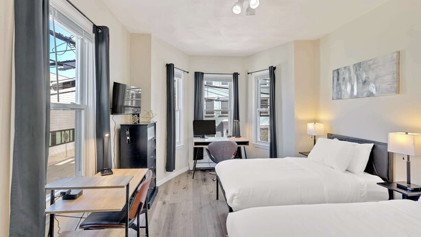 Une chambre d’hôtel avec deux lits, un bureau avec un ordinateur, une chaise et un téléviseur.