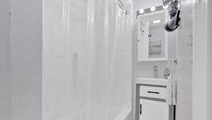 Une salle de bain moderne avec une baignoire, un lavabo et un miroir avec éclairage intégré.