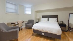 A bedroom with a bed, a desk, a chair, and a nightstand.