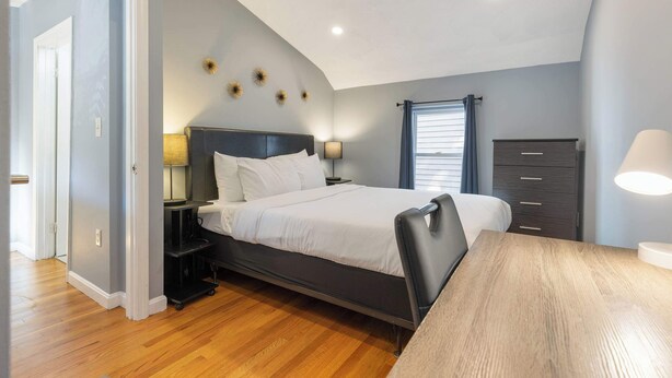 A bedroom with a bed, bedside tables, a dresser, and a desk. - Well Located 3 Bed, 1 Bath in Kendall Sq (Cambridge)