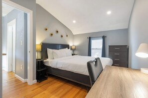 Ein Schlafzimmer mit einem Bett, Nachttischen, einer Kommode und einem Schreibtisch.