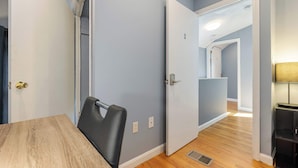 A room with a wooden table and a black chair, light blue walls, and a door leading to another room. - Well Located 3 Bed, 1 Bath in Kendall Sq (Cambridge)