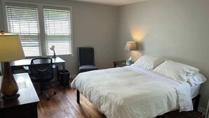 A bedroom with a bed, a desk, a chair, and two lamps. - Spacious 2BR Apt in the Heart of Fargo (Fargo)