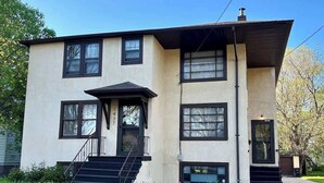 A two-story building with a flat roof, a front entrance with a door, and a staircase leading to the entrance. - Spacious 2BR Apt in the Heart of Fargo (Fargo)
