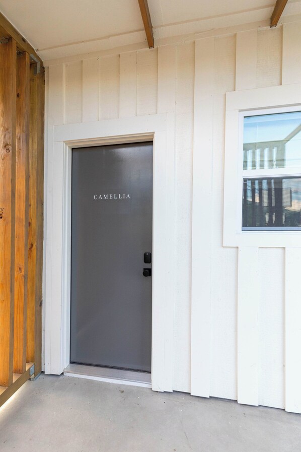 A white exterior wall with a door labeled 'CAMELLIA' and a window to the right.