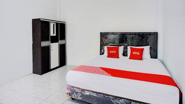 A hotel room with a bed, a wardrobe, and a red and white bedspread.