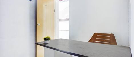 A room with a wooden door, a small potted plant, a table, and a chair.