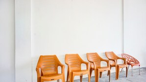 Five wooden chairs lined up against a white wall.