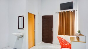 A room with a white sink, a wooden door, a brown curtain, and a red chair.
