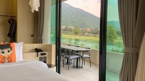 A hotel room with a bed, a table with chairs, a telephone, and a view of a mountainous landscape through large windows. - Viewpoint Khaoyai Hotel (Pak Chong)