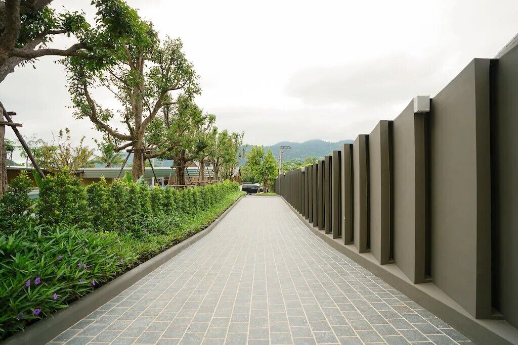 Un sendero pavimentado bordeado por follaje y una estructura de pared moderna.