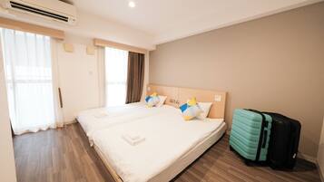 A hotel room with a large bed, a suitcase, and an air conditioning unit.