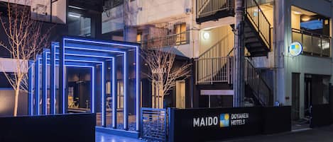 A hotel entrance with a modern design, a visible staircase, and a sign for Maido Hotels.