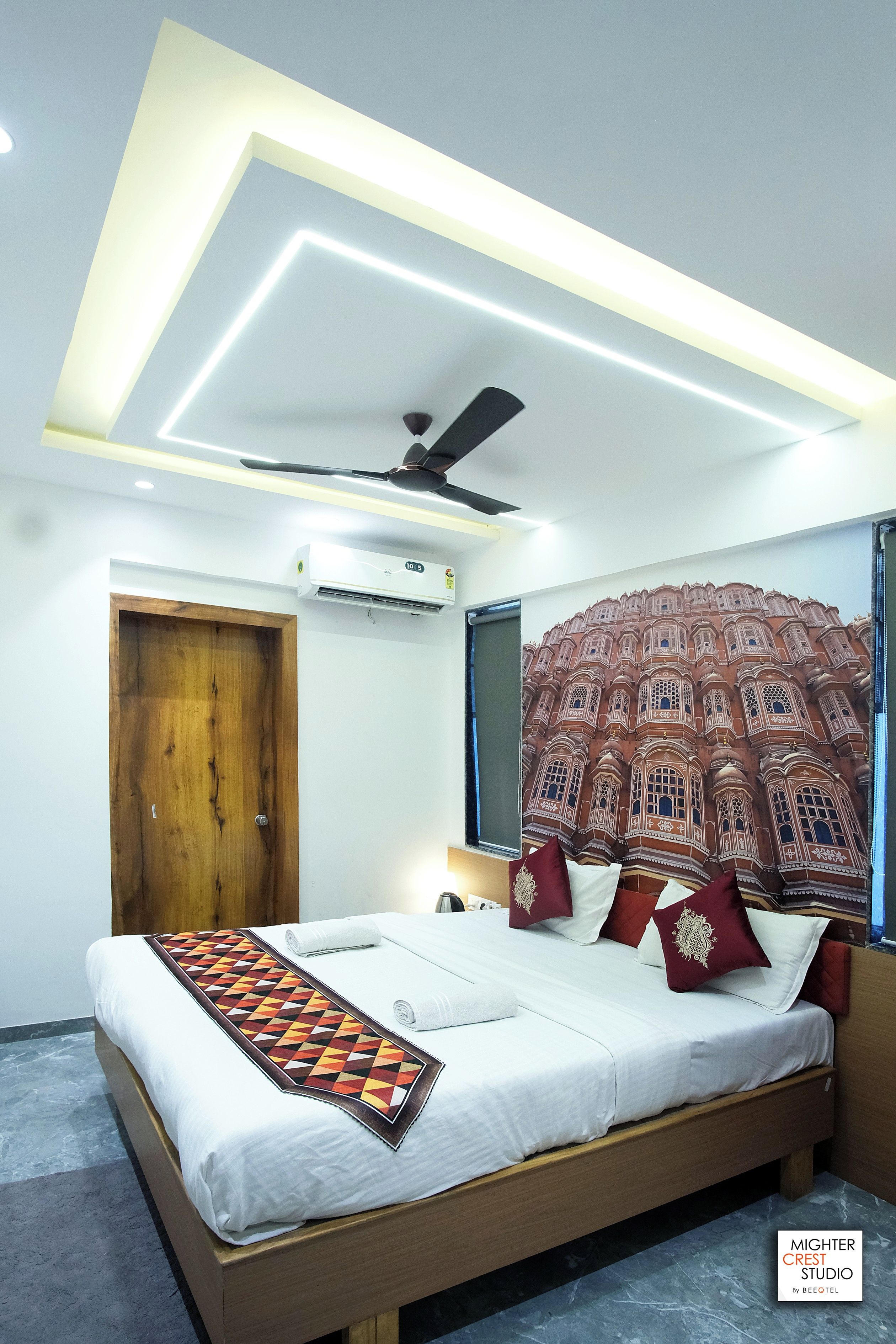 Una camera da letto moderna con un letto, un ventilatore a soffitto, un condizionatore d'aria e una parete con un murale.