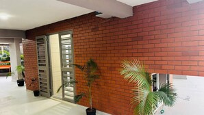 A spacious indoor area with a brick wall, a sliding glass door, and several potted plants. - Mighter Crest Studio Apartment (Nashik)