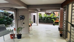 A spacious indoor area with a bench, potted plants, and a tiled floor. - Mighter Crest Studio Apartment (Nashik)
