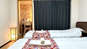 A hotel room with two beds, a desk, a chair, a brick wall, and a large window with curtains. - Cheap, 2-minute walk from the nearest station, 5 minutes to Namba by train, direct connection to Kansai International Airport, excellent access 【101 】. (大阪市)
