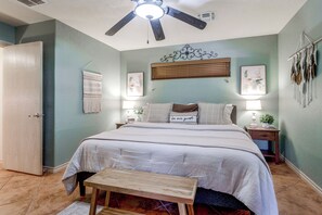 Une chambre à coucher comprenant un lit, des tables de chevet, un ventilateur de plafond et des éléments de décoration murale.