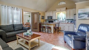 A living room with a sofa, a coffee table, and a blue leather chair. There is a kitchen area with cabinets and a microwave. - 1/2 Mi to Lake Lawtonka: Mtn-View Haven! (Medicine Park)