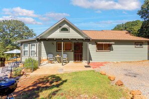 Einbungalow mit Veranda, Garage und einer kleinen Terrasse mit Gartenmöbeln.