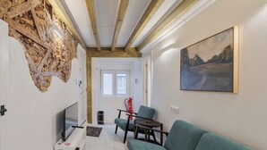 Un salon moderne avec un canapé de couleur turquoise, un téléviseur à écran plat et un tableau accroché au mur.