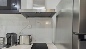 Une cuisine moderne équipée d’un réfrigérateur en acier inoxydable, d’un four encastré, d’un four à micro-ondes, d’un grille-pain et d’une bouilloire.