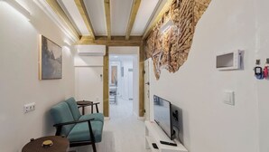 Un salon moderne avec un canapé, un téléviseur et un mur au revêtement original.