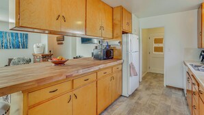 Una cocina con armarios de madera, encimera de madera, microondas, refrigerador y un cuenco de fruta.