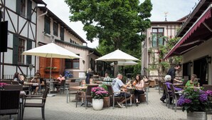 An outdoor café with tables and chairs, surrounded by buildings with traditional architecture. - Pension Töpferhof (Tangermünde)