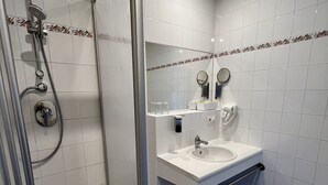 A bathroom with a glass-enclosed shower, a sink, a mirror, and a toilet. - Pension Töpferhof (Tangermünde)