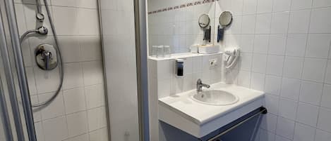 Une salle de bain avec une douche à parois de verre, un lavabo, un miroir et des toilettes.