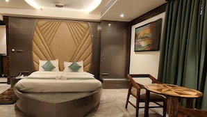 A modern hotel room with a large bed, a small wooden table, and a painting on the wall. - Daltin Tower Digha (Kanthi)