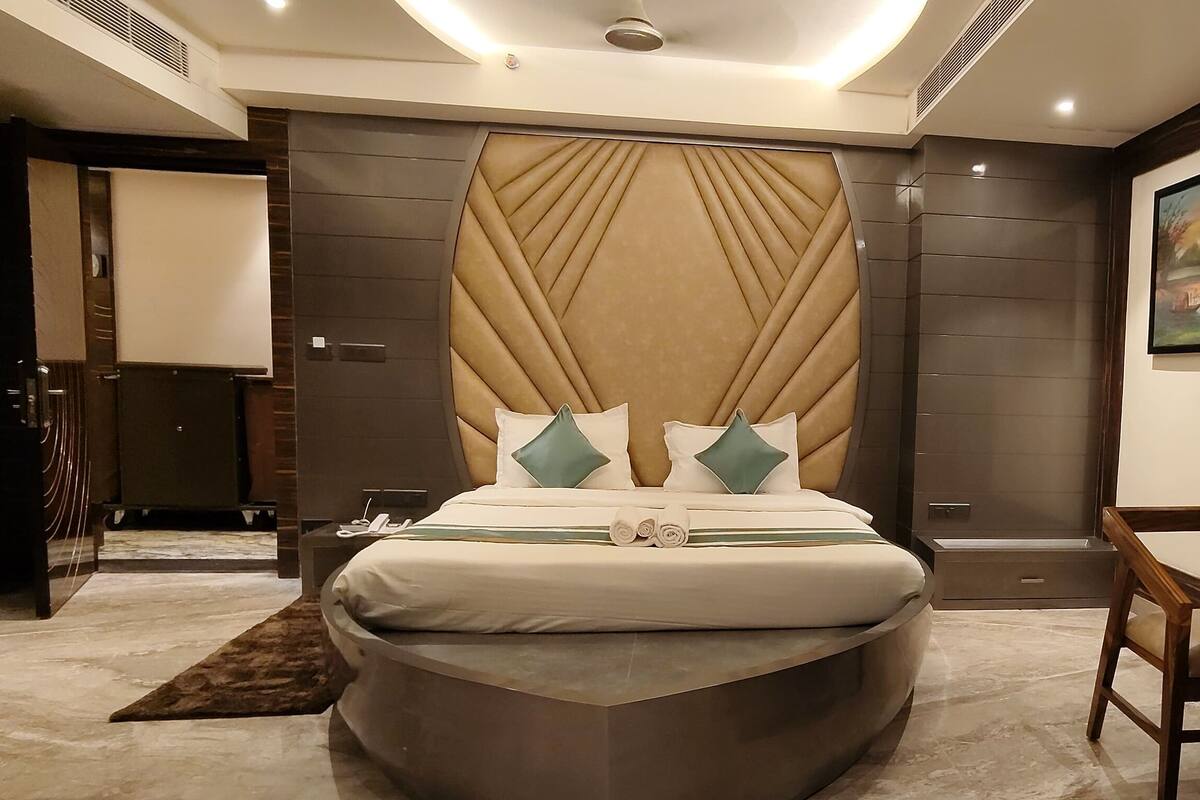 A modern hotel room with a large bed, a small wooden table, and a painting on the wall.