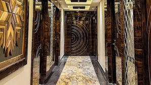 A hallway with a marble floor, decorative wall panels, and recessed lighting. - Daltin Tower Digha (Kanthi)