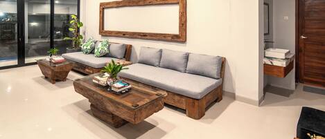 A modern living room with a grey sofa, wooden coffee tables, and a large framed picture on the wall.