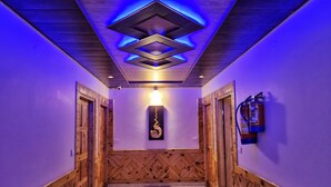 Un couloir avec des lambris en bois, un extincteur et un luminaire fixé au mur.