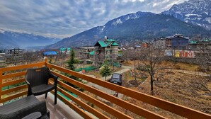 Un balcon offrant une vue sur un paysage montagneux, avec des sommets enneigés et un village aux bâtiments traditionnels.