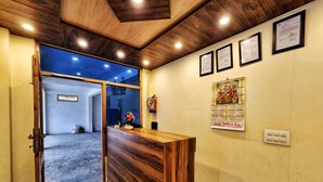 Un espace d’accueil avec un comptoir de réception en bois, un extincteur, des certificats encadrés accrochés au mur et un calendrier.