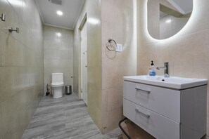 Ein modernes Badezimmer mit Toilette, Bidet und Waschbecken mit Spiegel.