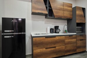 A kitchen with a black refrigerator, wooden cabinets, a white countertop, and a microwave. - Studio 4 Luxurious, 3-minute walk to the beach in an exclusive neighborhood. (Oranjestad)