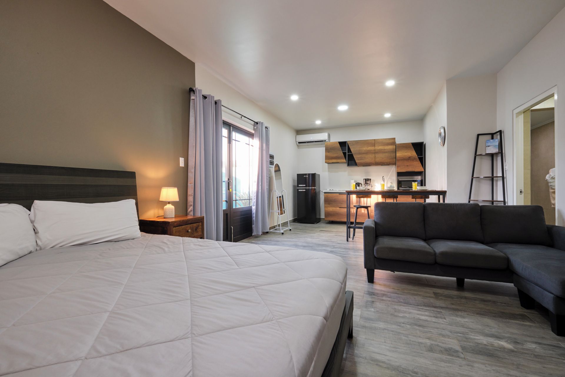 Une chambre d’hôtel comprenant un lit, un canapé, une kitchenette et un coin repas.