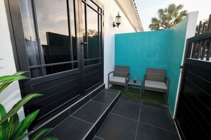 A small outdoor seating area with two wicker chairs, a small table, and a potted plant. - Studio 4 Luxurious, 3-minute walk to the beach in an exclusive neighborhood. (Oranjestad)