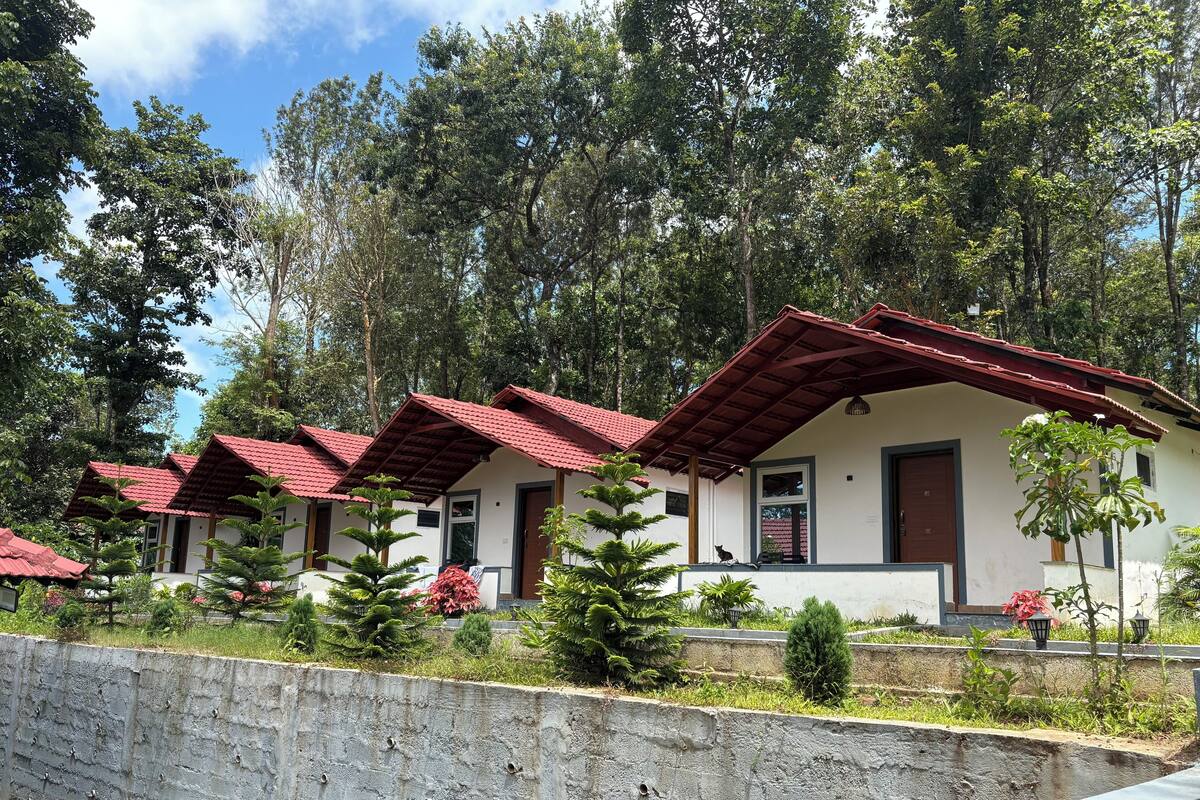 A row of small, white buildings with red roofs, surrounded by lush greenery and trees.