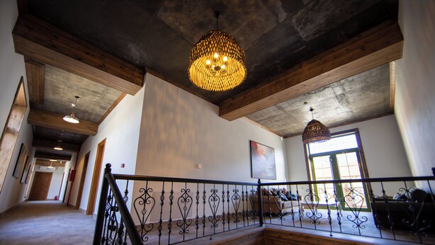 A staircase with a wrought iron railing, wooden beams, and a hanging light fixture. - Xinali Hotel Xizi  (Altiagach)