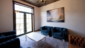 A spacious living room with a large window, a white coffee table, and two blue sofas. - Xinali Hotel Xizi  (Altiagach)