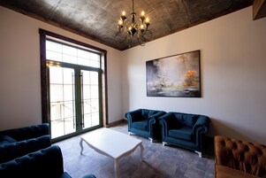 Un salón espacioso con un amplio ventanal, una mesa de centro blanca y dos sofás azules.